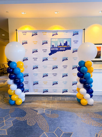 2 classic balloon columns with balloon toppers in front of a step and repeat at a corporate event in hartford, ct.
