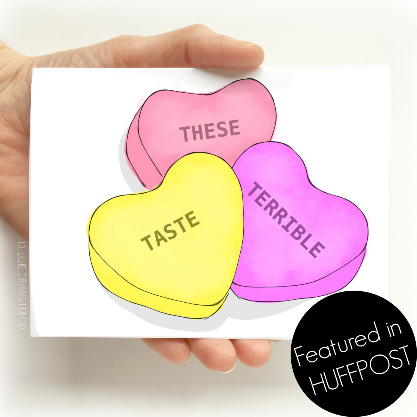 A white Valentine's day greeting card with images of three sweet Valentine's day candy hearts in colors of red, pink, and yellow and the words 'these' 'taste' 'terrible'