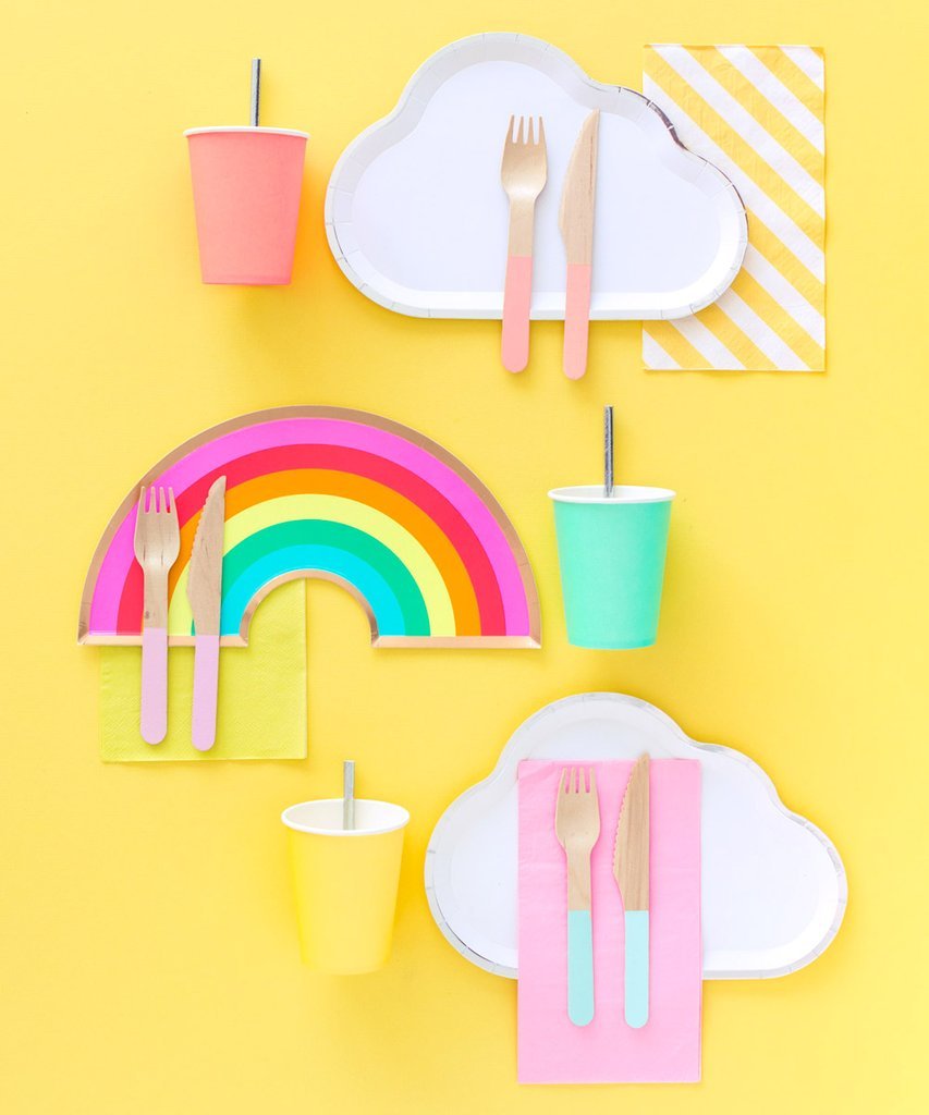 White cloud plates set with pink cups and cutlery paired with yellow striped napkins accompanied by a rainbow party plate.