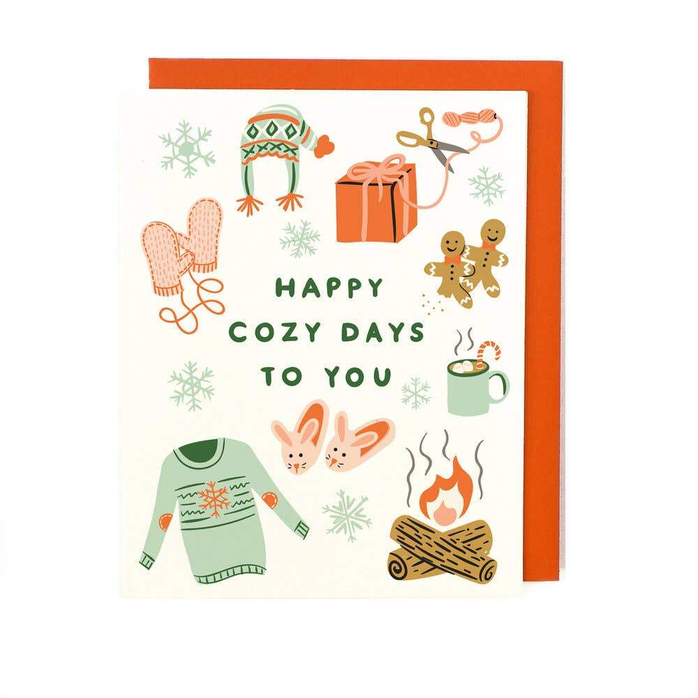 Cozy days holiday card displaying cozy items on the face of the card including a fire, holiday sweater, slippers, mittens, gingerbread men and other cozy items associated with the holiday. The face of the card reads 'Happy Cozy Days To You'