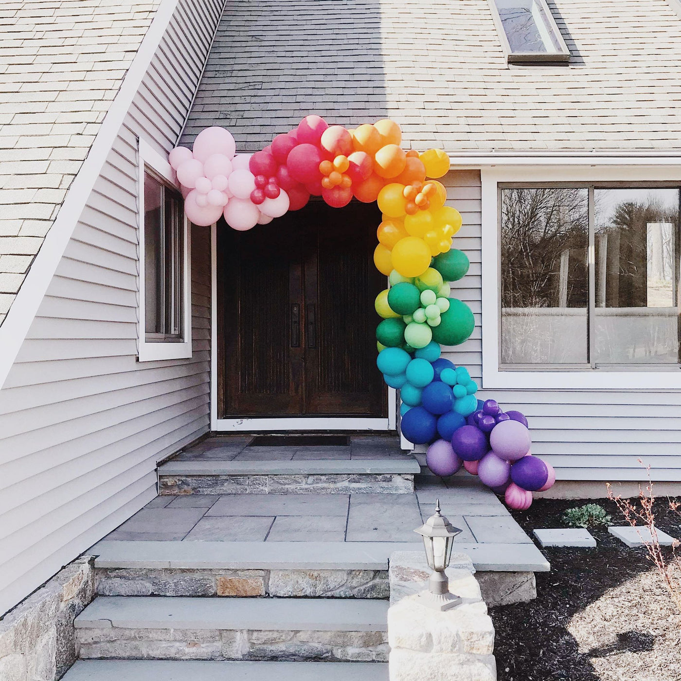DIY Balloon Garland in Rainbow Swirl assembled and installed around an entranceway to a home.