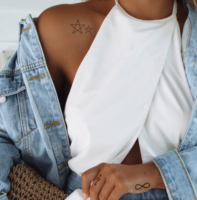 girl gang tattoos applied to a woman's shoulder two 5 sided stars in differing sizes