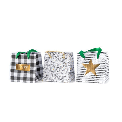 Holiday Mini Gift Bags in cute holiday designs such as black and white plaid, white with holiday style foliage, and white with black polka dots and a gold star.