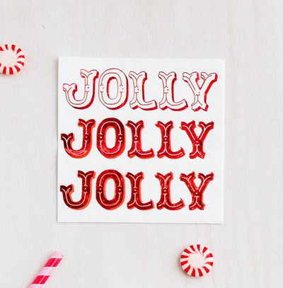 A Jolly holiday cocktail napkin set on a white background amongst red and white holiday mints