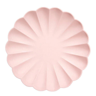A large pale pink eco friendly plate in a circular scalloped shape.