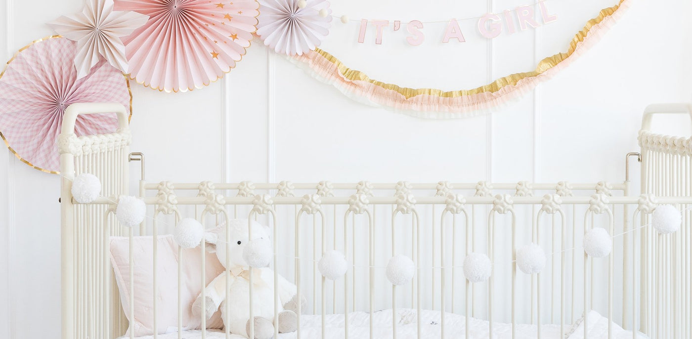 Cream Yarn Pom Poms hung in a nursery complimenting birthday décor